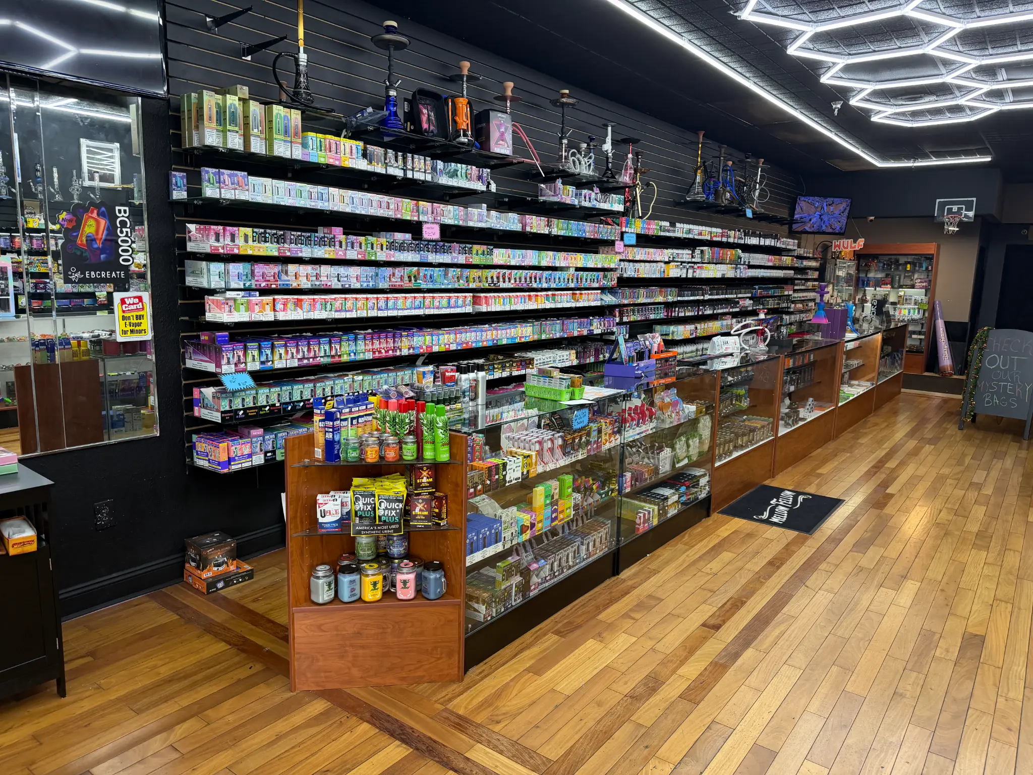 Puffology Smokeshop product wall featuring disposable vapes, glass pipes, and smoking accessories in Oak Park Plaza Brandon